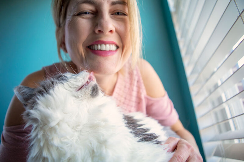 Un gato tratando de lamer su cara de hombre feliz.