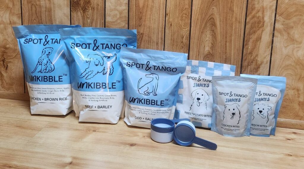 Envases de comida para perros Spot y Tango, todos alineados sobre una mesa.